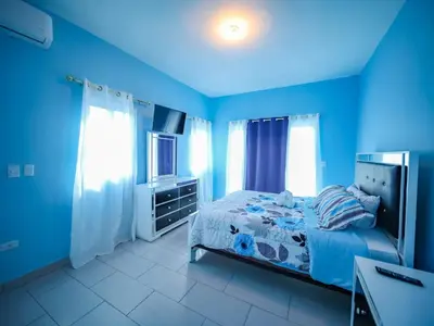 a blue bedroom with a bed and a television at 8BR Private Villa in Sosua 2 mins from Nightlife in Sosúa
