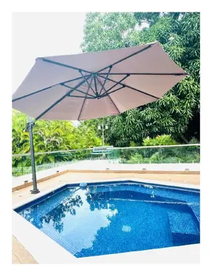 a large umbrella sitting next to a swimming pool at Casa De Campo Beautiful Villa with AC in the all house steps from the beach in La Romana