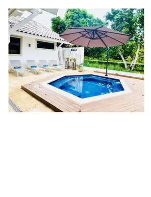 a swimming pool with an umbrella and chairs at Casa De Campo Beautiful Villa with AC in the all house steps from the beach in La Romana