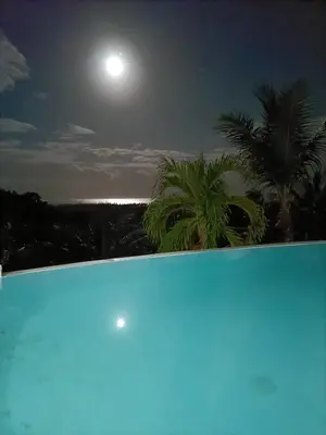 a view of the moon from a swimming pool at night at villa vue mer in Las Terrenas