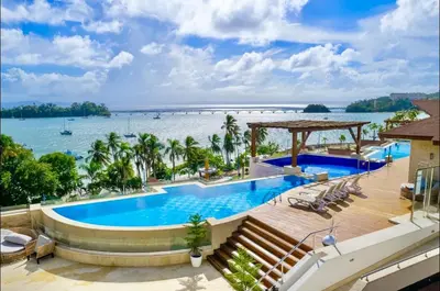 a resort swimming pool with a view of the water at Beautiful Apartment overlooking Samaná Bay