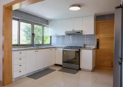 a kitchen with white cabinets and a stove top oven at La casa del lago in Cumayasa