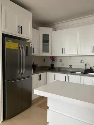 a kitchen with white cabinets and a stainless steel refrigerator at Moderno y Acogedor Apartamento detrás del Homs in Santiago de los Caballeros