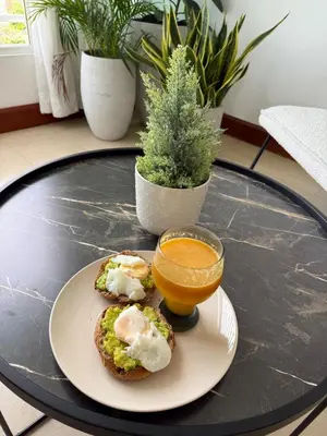 a plate of food with eggs and a bowl of orange juice at Moderno y Acogedor Apartamento detrás del Homs in Santiago de los Caballeros