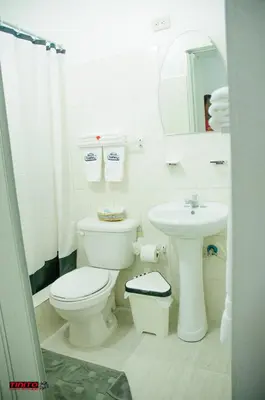 a white bathroom with a toilet and a sink at Batey Hotel Boutique in Boca Chica