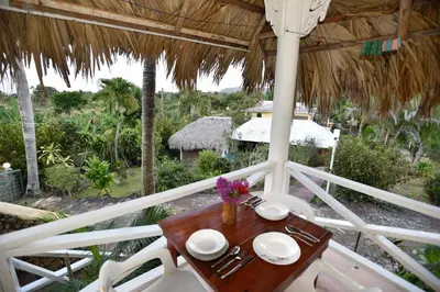 a table and chairs in a porch with a view of a garden at Las Mariposas in Las Galeras