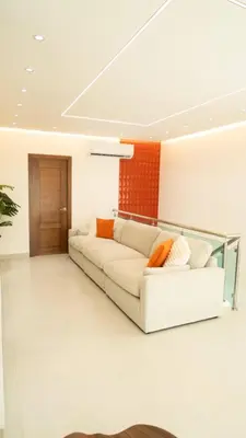 a white couch in a living room with an orange wall at Luxurious 3-Bedroom Retreat in Santiago de los Caballeros in Santiago de los Caballeros