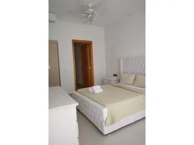 a white bedroom with a bed and a ceiling fan at Apartement cosy et lumineux in Cuevas