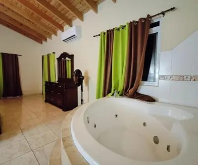 a large white tub in a room with green curtains at Aura Azul in Sosua