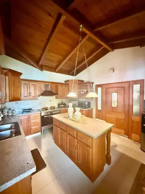 a large kitchen with wooden cabinets and a large island at Hermosa y acogedora Villa en Casa de Campo in La Romana