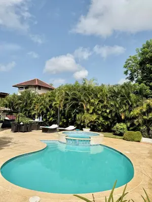 a large swimming pool in a yard with trees at Hermosa y acogedora Villa en Casa de Campo in La Romana