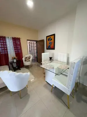 a living room with a glass table and white chairs at Cruzairbnb in San Felipe de Puerto Plata
