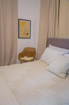 a bedroom with a bed with a chair next to it at Cozy Loft In The Heart of Santo Domingo Este in Juan López