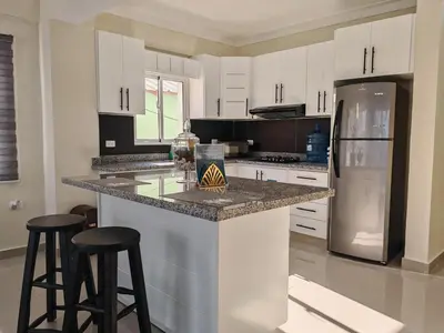 a kitchen with white cabinets and a counter with stools at 2 Bdrm, Wi-fi, Hot Water Near Beach and River, 2R in Paraíso