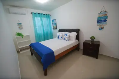 a bedroom with a bed with blue sheets and a nightstand at Horizonte Marino En De Franchecis Hostal in Juan Dolio