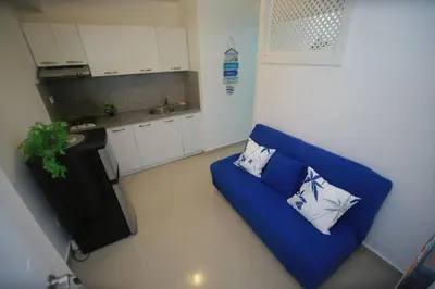 a living room with a blue couch and a kitchen at Arena blanca Franchecis hostal in Juan Dolio