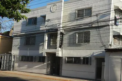 a white building with a clock on top of it at Arena blanca Franchecis hostal in Juan Dolio