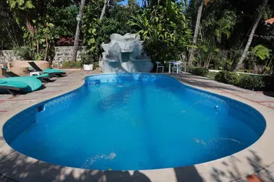 a large blue swimming pool with a fountain at Arena blanca Franchecis hostal in Juan Dolio