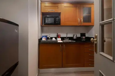 a small kitchen with wooden cabinets and a microwave at Catalonia Santo Domingo in Santo Domingo