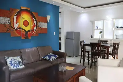 a living room with a couch and a dining room at Cozy apartment AC, Hot Water, WiFi, Pool, Bar, Bani 203 in Baní