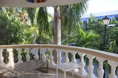 a white balcony with a bench and palm trees at Cozy apartment AC, Hot Water, WiFi, Pool, Bar, Bani 203 in Baní
