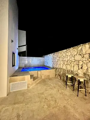 a swimming pool in a stone wall with two tables at Laggo one houses in Punta Cana