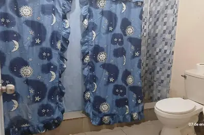 a bathroom with a toilet and a blue shower curtain at Escape to the countryside peace andnature in Bonao in Bonao