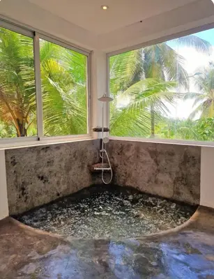 a bathtub in a room with two windows at Grandi spazi vista mare piscina infinity con grotta taina in Las Terrenas