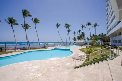 a swimming pool next to a beach with palm trees at Beach Front Condo!