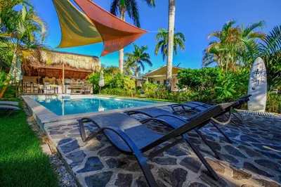a pool with a chair and an umbrella at Hotel Enjoy in Las Terrenas