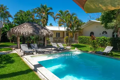 a swimming pool with chairs and a house at Hotel Enjoy in Las Terrenas