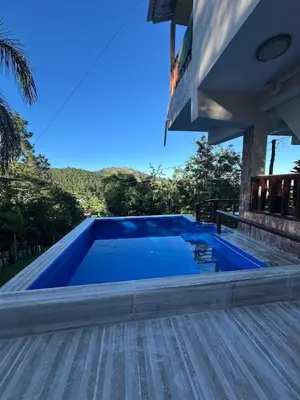 a large swimming pool on a deck with a house at Mirador de las Nubes in Jarabacoa