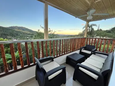 a porch with chairs and a balcony with a view at Mirador de las Nubes in Jarabacoa