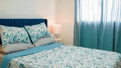 a bedroom with a bed with a blue blanket and a window at Relaxing & New Retreat 3 bedroom riviera Verde in Santo Domingo