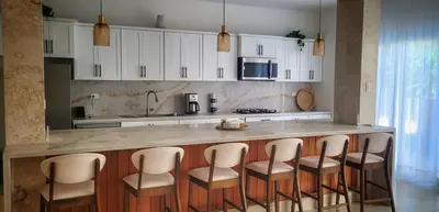 a kitchen with a counter with stools around it at Villa Jasmine Ocean Village in Sosúa