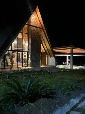 a house at night with a palm tree in front of it at La Gloria in San José de Ocoa