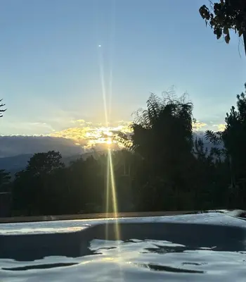 a swimming pool with the sun setting in the background at La Gloria in San José de Ocoa