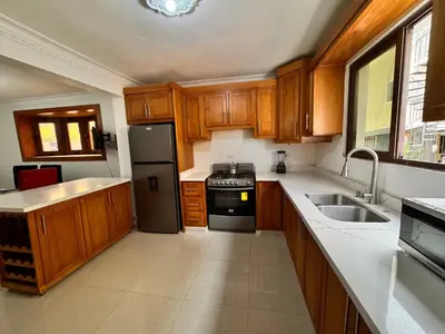 a kitchen with wooden cabinets and a black refrigerator at Enjoy Huge 4 bedrooms, and 3 bathrooms, 8 new apartments in Santiago de los Caballeros