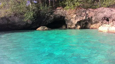 a pool of blue water in front of a cave at Casa de las Mariposas - near the beach in Río San Juan