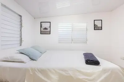 a white bed in a white room with a window at Casa de las Mariposas - near the beach in Río San Juan