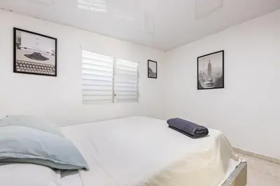 a white bedroom with a bed and a window at Casa de las Mariposas - near the beach in Río San Juan