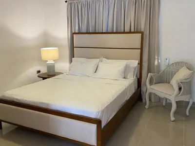 a bedroom with a bed and a chair and a lamp at Apartamento San Pedro Colonial in San Pedro de Macorís
