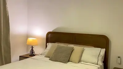 a bed with white pillows and a lamp on a table at Apartamento San Pedro Colonial in San Pedro de Macorís