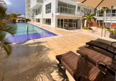 a swimming pool with two benches next to a building at MarMary Ocean view by Marina in Boca Chica