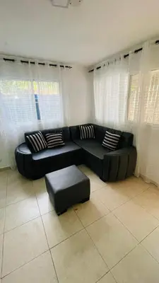 a living room with a black couch and a stool at beach apartment cafe del sol in La Puntica de Juan Dolio