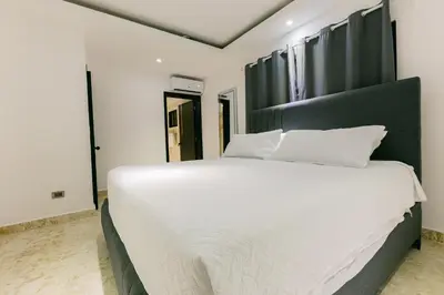 a bedroom with a large white bed with a black headboard at Arena Aparta Hotel in Punta Cana
