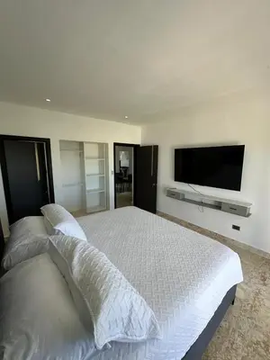 a bedroom with a white bed with a flat screen tv at Arena Aparta Hotel in Punta Cana