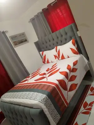 a bed with red and white blankets and pillows at Apartamento Alto del valle de 2 habitaciones in Santiago de los Caballeros