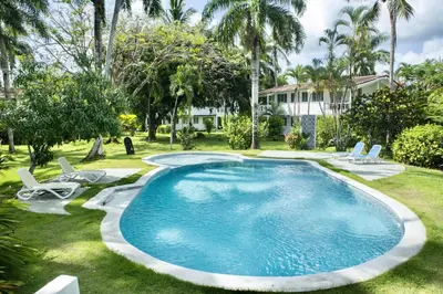 a swimming pool in a yard with chairs and a house at Punta Poppy beach Apt 3 minutes walk Oasis Hotel in Las Terrenas