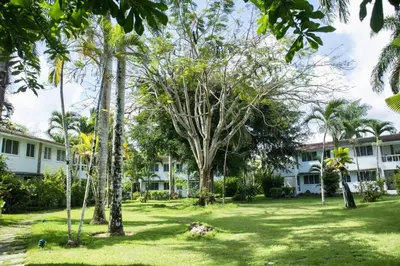 a park in front of a building with palm trees at Punta Poppy beach Apt 3 minutes walk Oasis Hotel in Las Terrenas